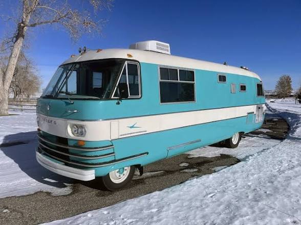 A vintage teal Winnebago motorhome parked in the snow